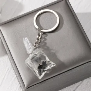 Detailed close-up shot of the transparent resin fish keychain resting elegantly on a soft grey box.