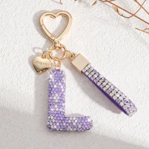 Gros plan détaillé d'un porte-clés lettre en strass violet scintillant avec fermoir en cœur.