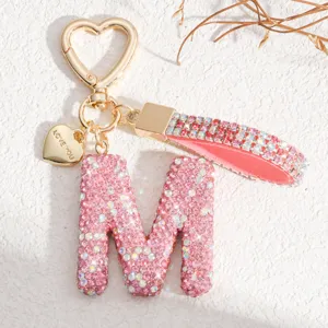Gros plan du détail de porte-clés lettre M en strass rose avec fermoir en cœur chic.