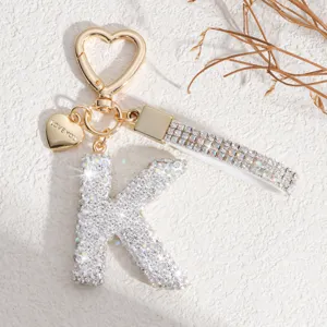 Gros plan d'un porte-clés lettre en strass étincelant avec fermoir cœur et pendentif amour.