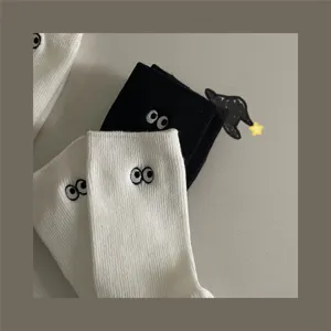 Vue détaillée de chaussettes mignonnes brodées d'yeux en style noir et blanc classique.