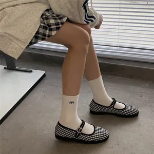 Chaussettes mi-hautes blanches mignonnes avec broderie d'yeux et chaussures à carreaux.