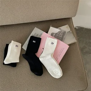 Gros plan de chaussettes mi-hautes noires et blanches avec des motifs brodés d'yeux mignons.