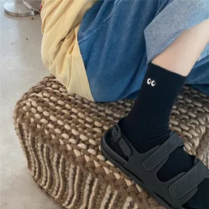 Vue de détail de jolies chaussettes noires en coton avec broderie de petits yeux.