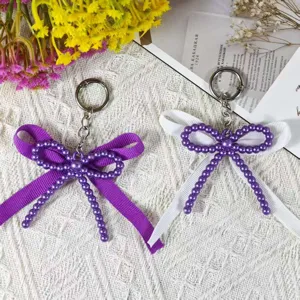 Handmade double bow keychain featuring elegant imitation pearls and soft ribbon in dual chic colors.