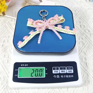 Handmade DIY imitation pearl double layer bow keychain with lace pendant detail view.