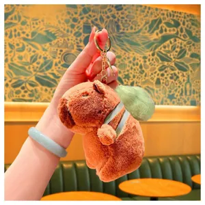 Cute capybara plush keychain detail view, featuring a soft brown toy with green backpack.