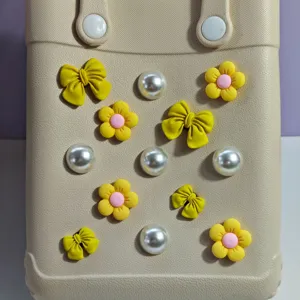 Vista dettagliata della borsa mare EVA con fiocchi gialli, fiori e decorazioni di perle.