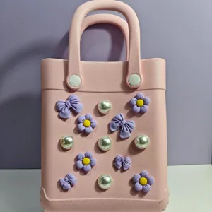 Dettaglio borsa da spiaggia in EVA rosa con fiocchi viola e perle. Accessorio borsa vacanza ideale.