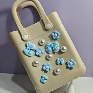 Borsa da spiaggia in EVA beige dettaglio con graziosi fiori blu e accessori di perle.