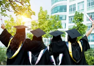Detail van het afstudeerseizoen met studenten in toga en hoed die buiten feestvieren.
