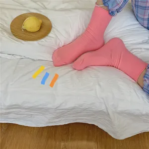Nahaufnahme Detailansicht rosa gerippter Mittelsocken auf weißem Bett mit Holzdeko.