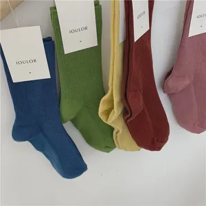 Gros plan de chaussettes unies en coton suspendues au mur, douces et élégantes.