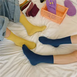 Detailaufnahme einfarbiger gerippter Baumwollsocken in Gelb und Blau mit feiner Herbsttextur.