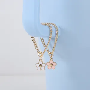 Close-up detail of cute smiling flower cup chain with gold chunky links and pastel charms.