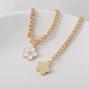 Close-up of gold-tone chunky chain with white enamel smiley flower pendant for cup.
