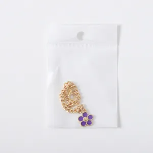 Details of the gold-tone chunky chain featuring a purple smiley flower pendant, cup charm accessory.