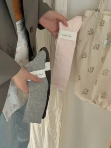Detailed view of basic ribbed calf socks in pastel pink and grey tones with paper packaging.