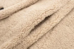 Close up view of cozy beige teddy fleece fabric texture, soft and warm winter coat material.