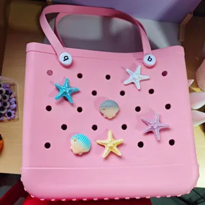 Pink EVA beach tote bag with cute starfish and seashell charms, perforated design for summer.