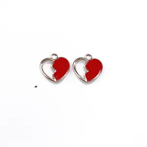 Vista dettagliata di due ciondoli in metallo a forma di cuore spezzato rosso per bijoux DIY.