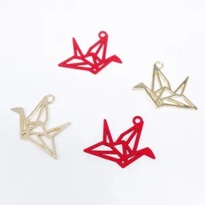 Nahaufnahme von geometrischen Origami-Kranich-Metallanhängern, rot und goldener Schmuck.