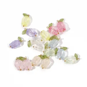 Detailed view of colorful glass tulip charms with green leaves and gold loops for DIY jewelry.