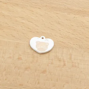 Close-up of white heart alloy charm with cute bear face, ideal for DIY jewelry making.