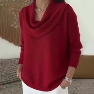 Detalle de jersey rojo de punto con cuello drapeado que muestra textura suave y elegante.