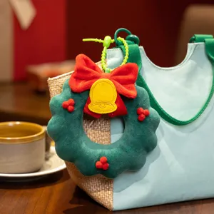 Cute Christmas plush wreath bag charm with red bow and bell pendant, soft holiday gift decoration.
