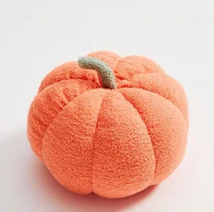 Detailed close-up of soft orange pumpkin plush throw pillow with green stem, cozy home decor.