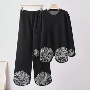 Ensemble en tricot noir avec haut à col rond et pantalon à broderie blanche pour femme.