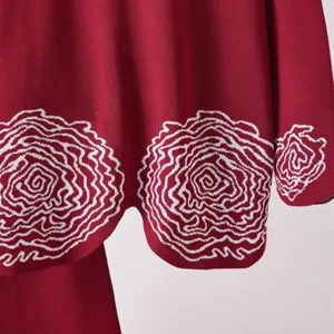 Détail de pull en tricot rouge élégant avec motif en spirale blanc et fine texture.