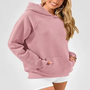 Détail de sweat à capuche rose côtelé avec texture, manches longues et poche avant.