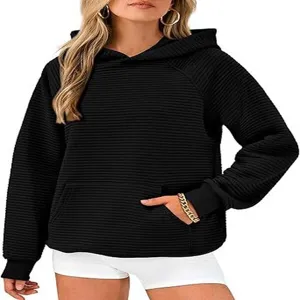 Gros plan sur la texture détaillée de la poche et des manches du sweat à capuche noir.