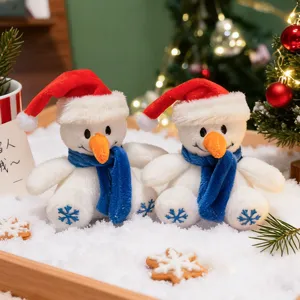 Gros plan détaillé de mignons bonhommes de neige en peluche avec bonnets rouges sur la neige.
