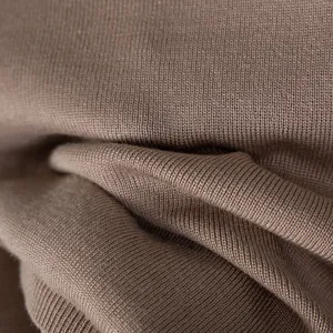 Primer plano detallado de tejido de punto marrón suave con textura acanalada y pliegues.