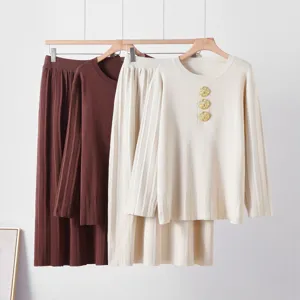 Ensemble pull en tricot avec boutons dorés et jupe plissée, détail de tenue élégante femme.