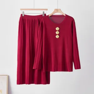 Ensemble élégant de haut en tricot rouge et de jupe longue plissée aux boutons dorés.