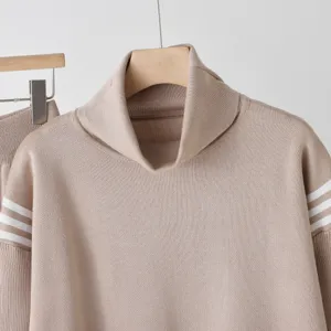 Detailed view of women's turtleneck knit sweater in khaki with white striped sleeves.