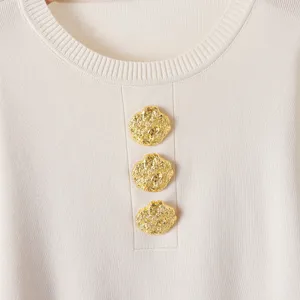 Vue en gros plan d'un haut en tricot chic avec encolure ronde et boutons dorés décoratifs.