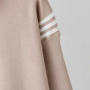 Detail shot of women's knit sweater sleeve featuring contrasting three stripes design.