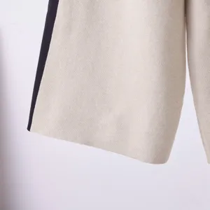 Close-up detailopname van zachte gebreide stof in beige met zwarte zijstreep.