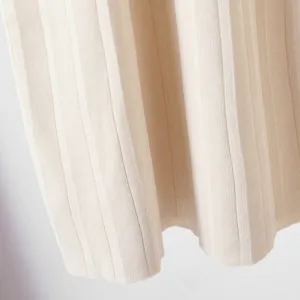 Gros plan sur un tissu en tricot côtelé beige avec texture plissée, matériau doux et fin.