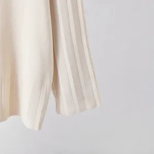 Détail de la manche du haut en tricot, tissu texturé côtelé blanc cassé, doux et confortable.