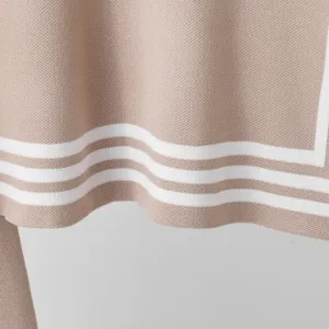 Close-up detail of beige knitted sweater hem with elegant white stripe pattern design.