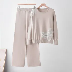 Beige knit two-piece set with beaded butterfly motif, cozy crewneck sweater and wide-leg pants.