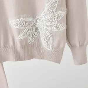 Detail view of the elegant pink knit sweater featuring exquisite pearl beaded butterfly appliqué.