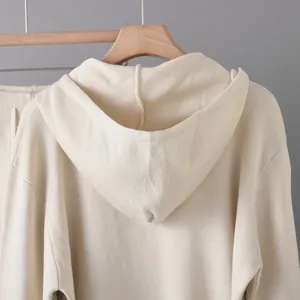 Dettaglio felpa con cappuccio in maglia, pullover crema, tessuto morbido, stile casual accogliente.