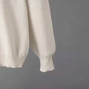 Primo piano dettagliato di un elegante maglione beige decorato con scintillanti strass.